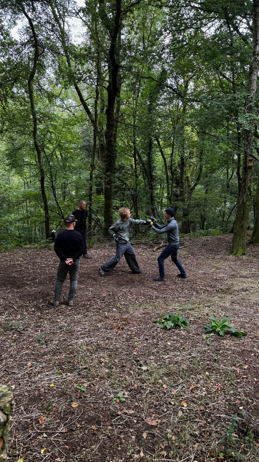 Two pairs sparring with sticks in the woods
