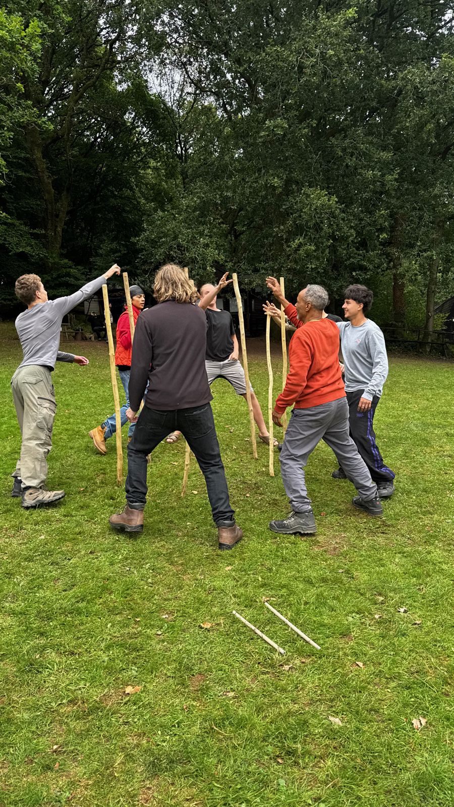 Boys and men playing a game with staffs on the grass
